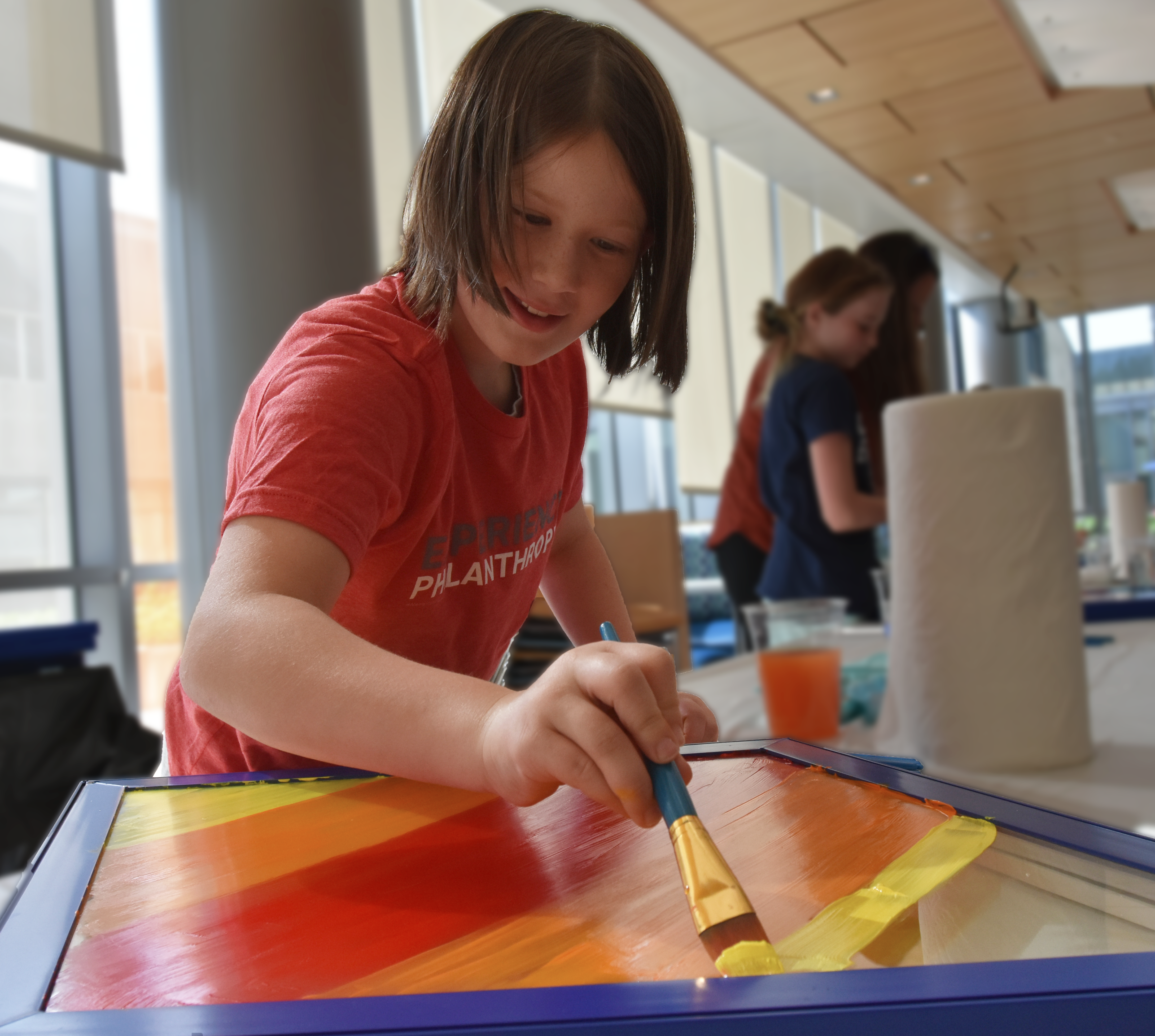 A young girl painting a window sash at a MITER Foundation and Four Diamond's Event